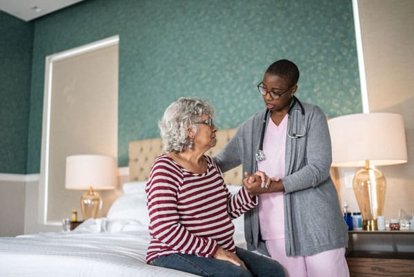 caregiver helping patient in bed at home | TLC Your Way Hospice Care